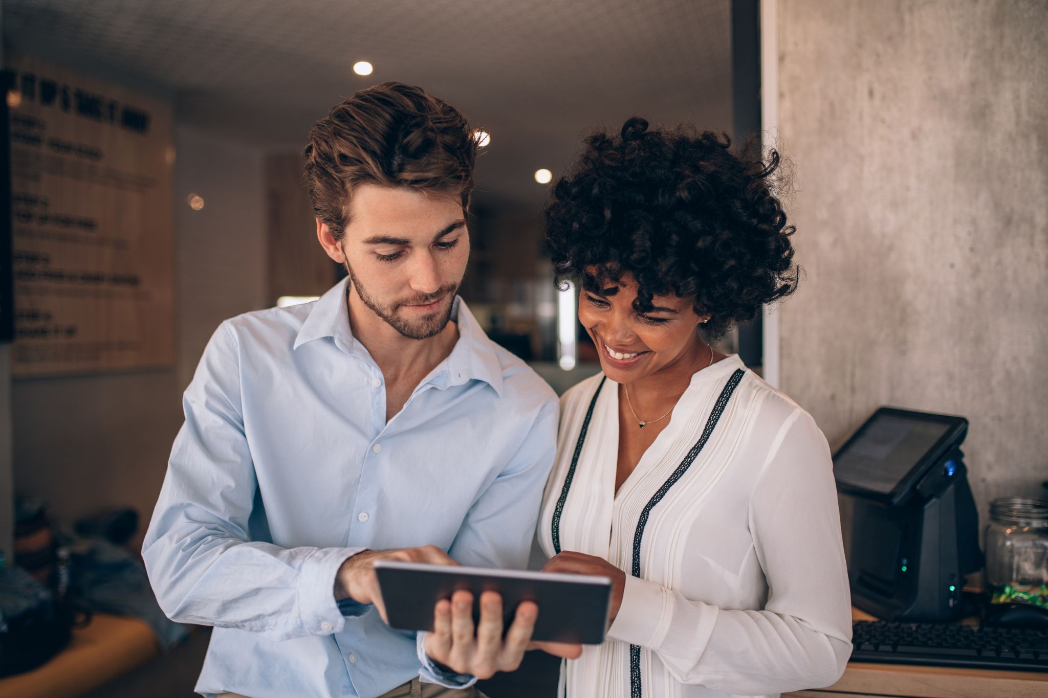 Image depicting two people looking at a tablet, this represents collaboration